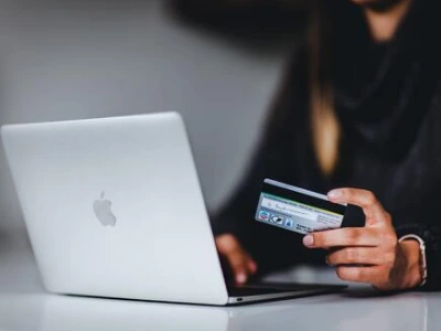 person on laptop with debit card in hand