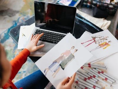 Person planning out designs for fashion with laptop